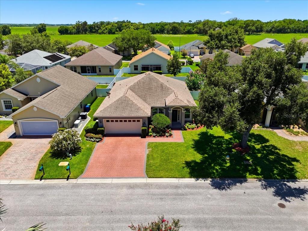 An aerial view shows a suburban house with a brick driveway and a large tree — 3221 OAK TREE LANE, WINTER HAVEN, FL