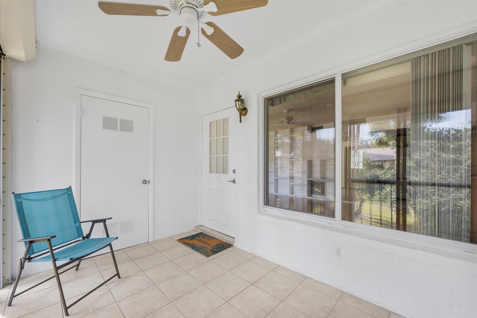 A covered patio features white walls, tiled flooring, a ceiling fan, and a blue chair — 313 Pine Ridge Circle # 2, FL 33463, FL