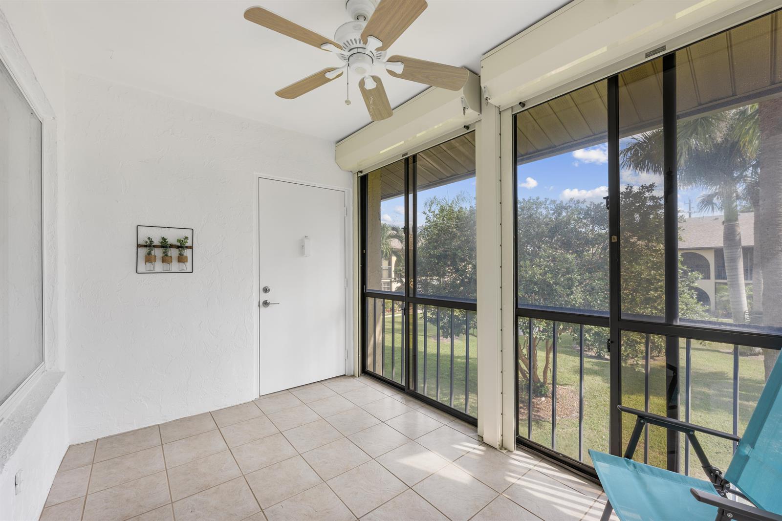 A sunroom with tiled flooring, a ceiling fan, a white door, and large screened windows — 313 Pine Ridge Circle # 2, FL 33463, FL