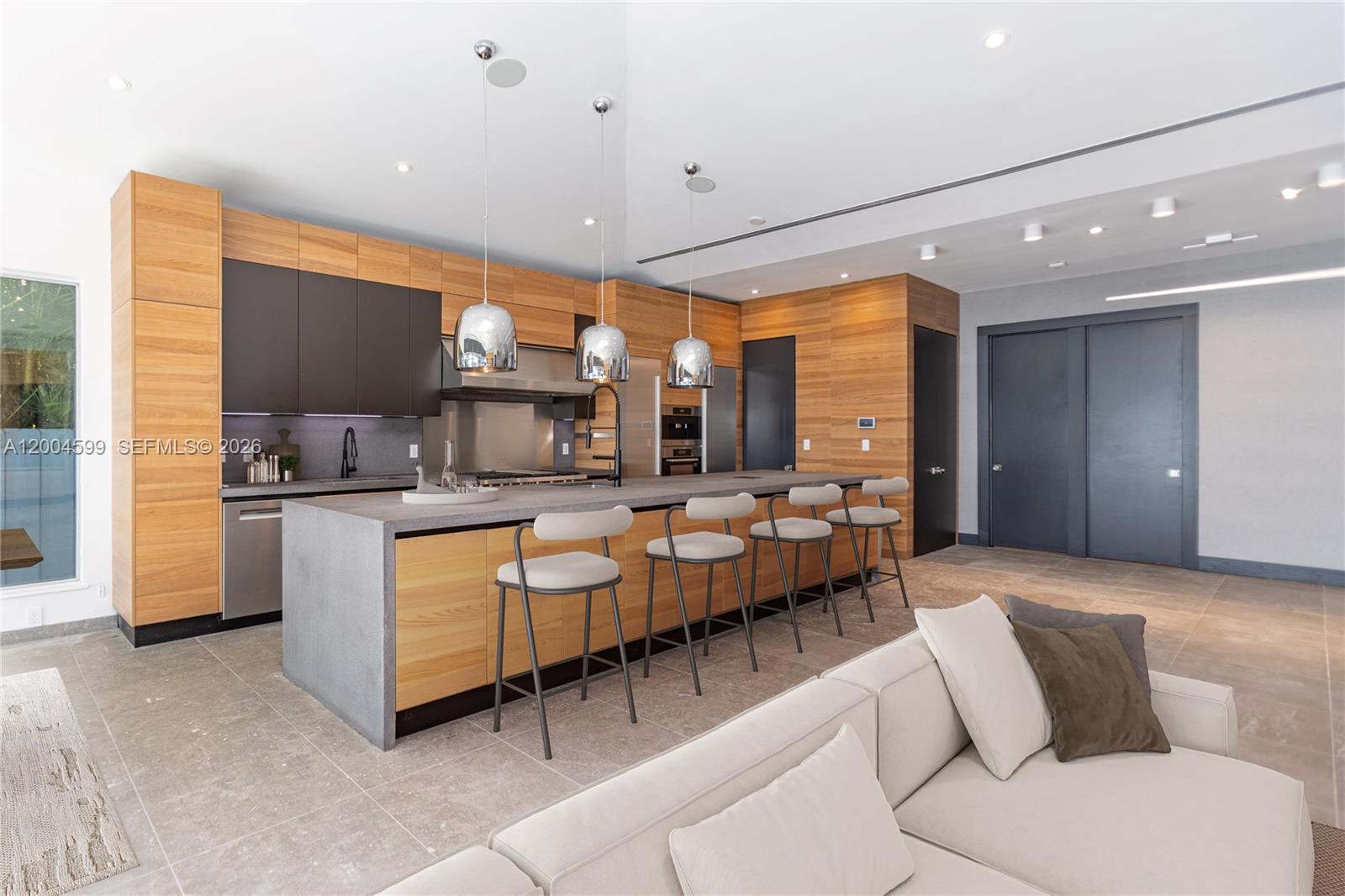 A modern kitchen features wood cabinetry, a concrete island, and four bar stools — 2440 N Shore Ter, Miami Beach FL 33141, MIAMI BEACH, FL