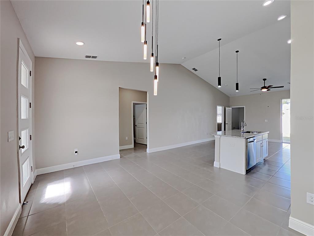 An open-concept living area features light tile flooring, a kitchen island, and pendant lighting — 309 FERN COURT, KISSIMMEE, FL