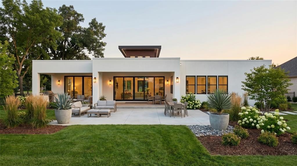 A modern house exterior features a covered patio, large glass sliding doors, and a fire pit — 142 TRANQUIL MIRROR LAKE COURT Lot 18, CLERMONT, FL