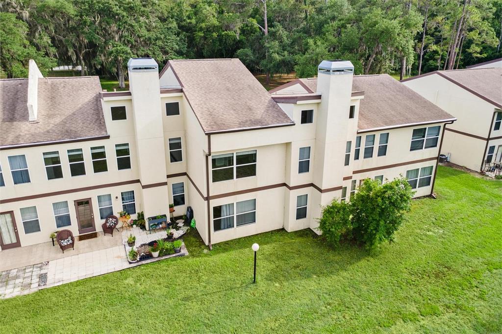 An aerial view of the rear exterior of a multi-story townhouse with a patio — 23202 SANDALWOOD DRIVE UNIT 202, WILDWOOD, FL