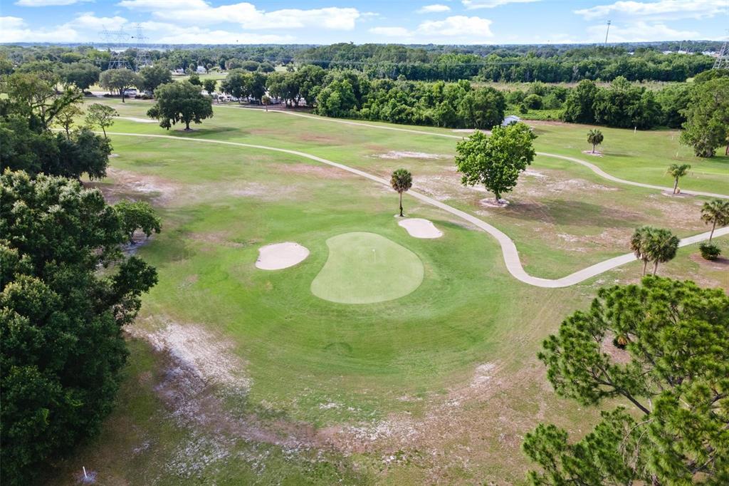 An aerial view of a golf course green surrounded by sand traps and trees — 23202 SANDALWOOD DRIVE UNIT 202, WILDWOOD, FL