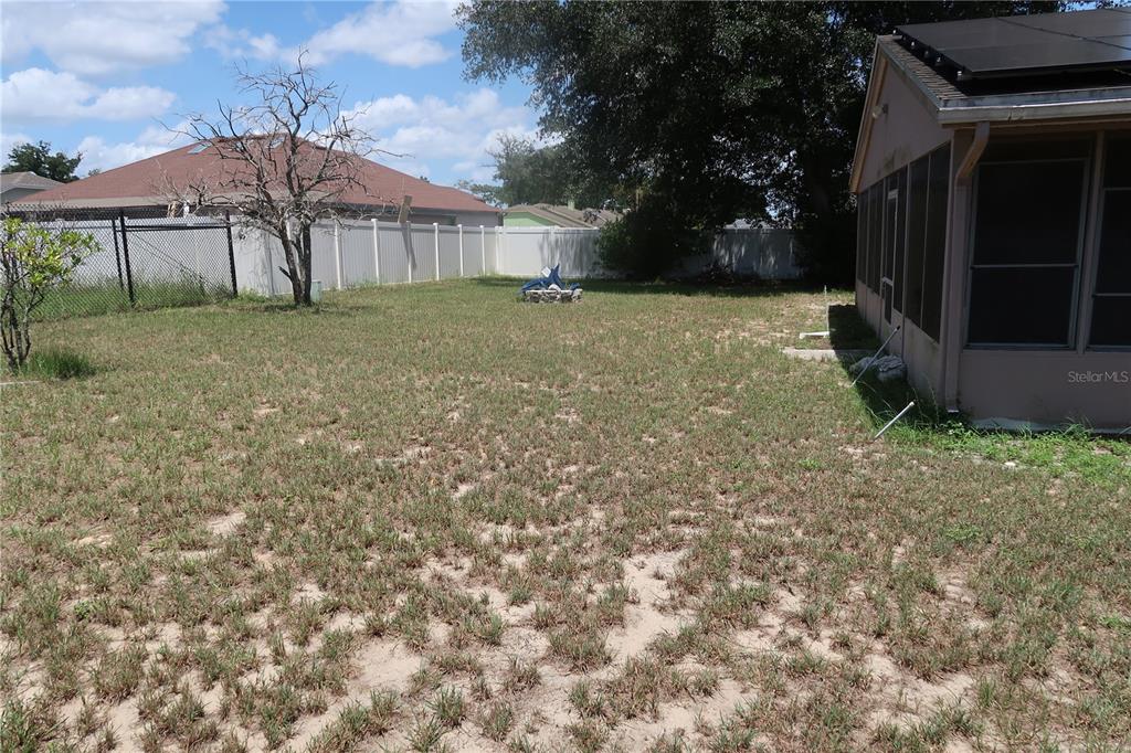 A grassy backyard features a bare tree, a white vinyl fence, and a screened-in porch — 7337 HIGH LAKE DRIVE, ORLANDO, FL