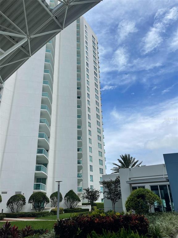 A tall white residential high-rise building stands against a blue sky with scattered clouds — 241 RIVERSIDE DRIVE UNIT 410, DAYTONA BEACH, FL