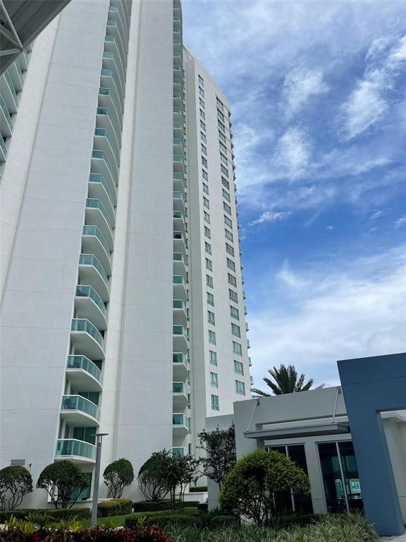 A tall white high-rise residential building with stacked balconies stands against a blue sky — 241 RIVERSIDE DRIVE UNIT 410, DAYTONA BEACH, FL