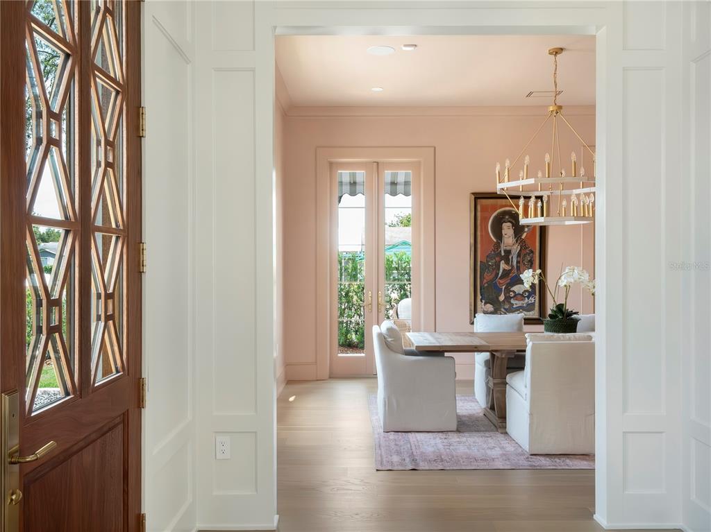 A dining room with pink walls, a wooden table, and a chandelier viewed through a doorway — 541 W CANTON AVENUE, WINTER PARK, FL