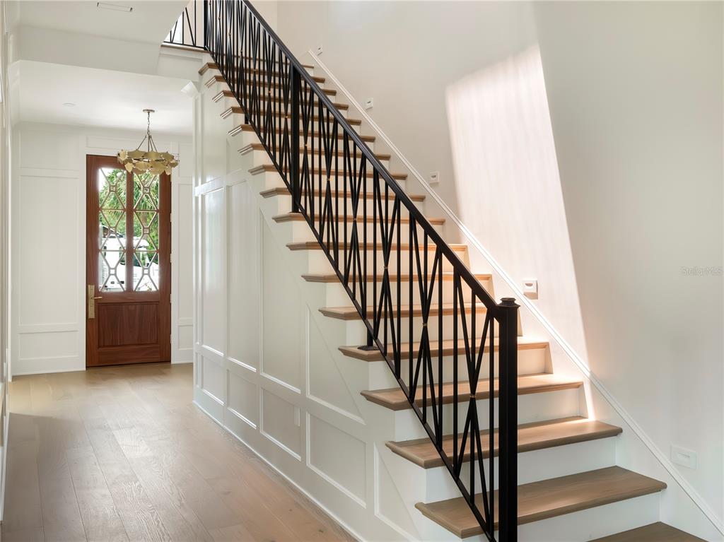 A staircase with wooden treads and a black metal railing sits in a white foyer — 541 W CANTON AVENUE, WINTER PARK, FL
