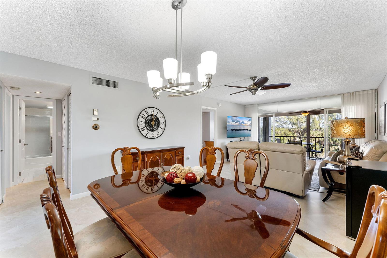 A dining room with a wooden table and chairs, a chandelier, and a wall clock — 3930 Inverrary Boulevard # d, Lauderhill FL 33319, LAUDERHILL, FL