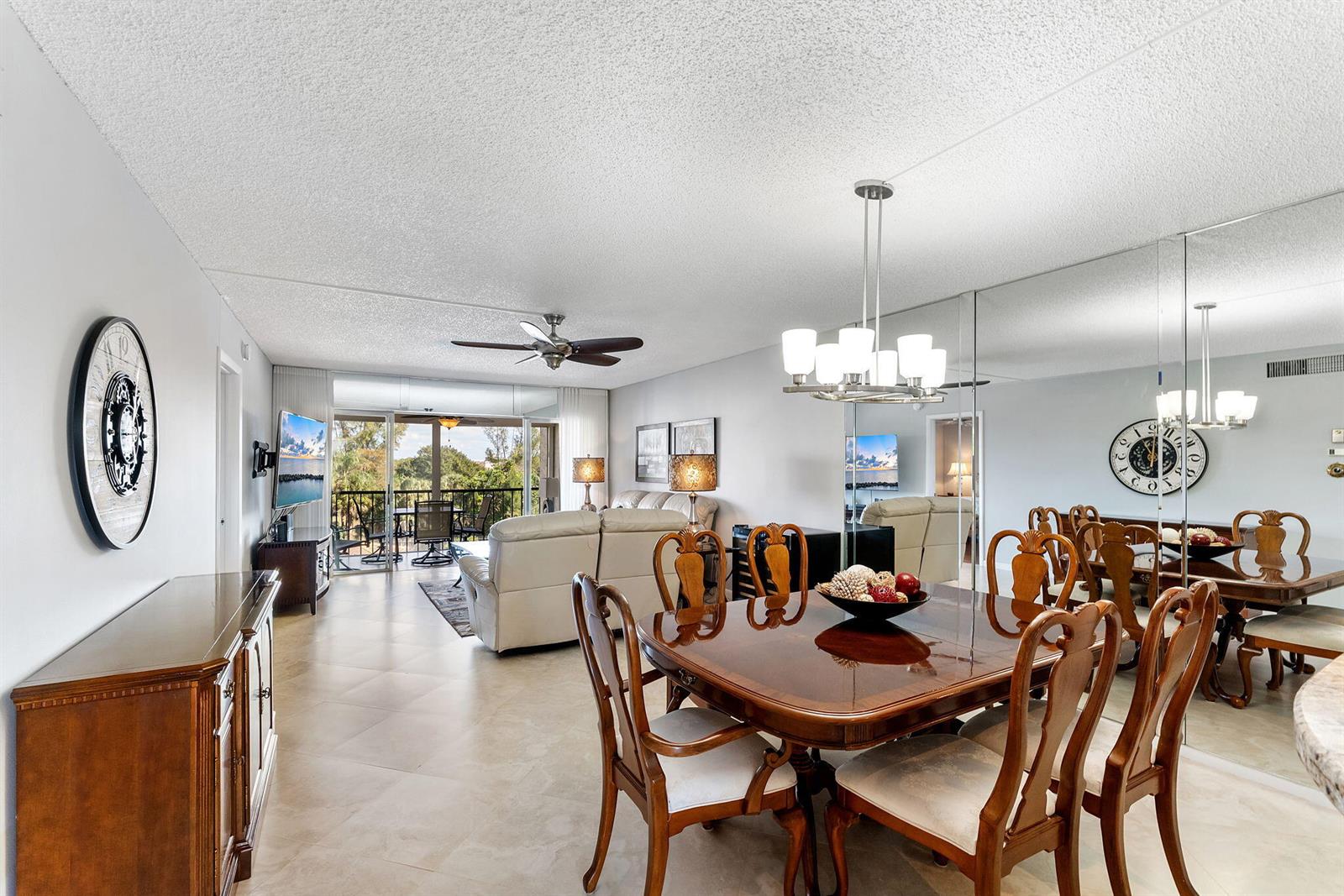 A dining area with a wooden table and chairs sits before a large mirrored wall — 3930 Inverrary Boulevard # d, Lauderhill FL 33319, LAUDERHILL, FL