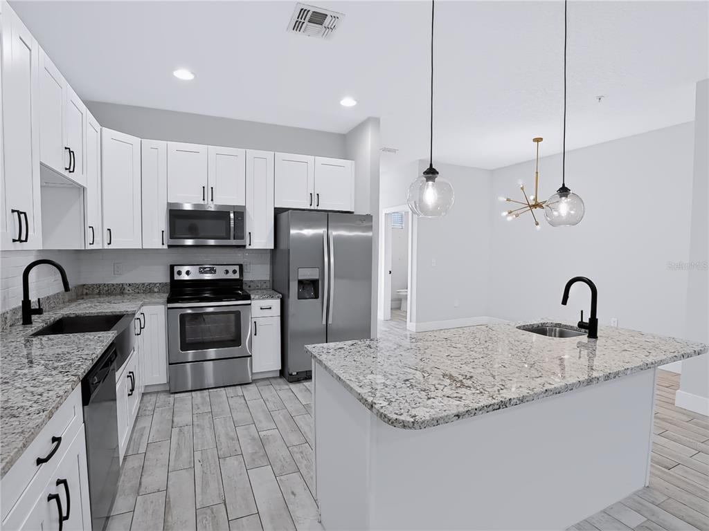 A modern kitchen features white cabinets, granite countertops, stainless steel appliances, and a center island — 2233R E KALEY AVENUE UNIT 6, ORLANDO, FL