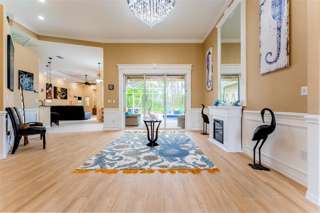 A living room with a chandelier, area rug, fireplace, and sliding doors to a pool — 1009 CAMPBELL STREET, PORT CHARLOTTE, FL