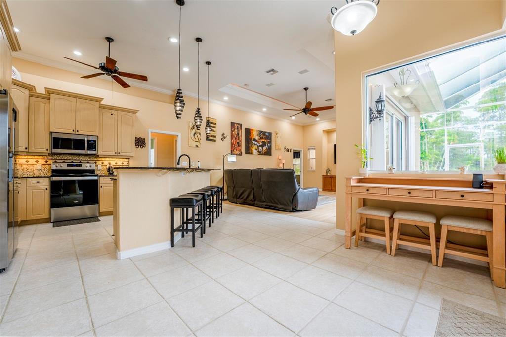 A kitchen with light wood cabinets and a breakfast bar opens into a living area — 1009 CAMPBELL STREET, PORT CHARLOTTE, FL