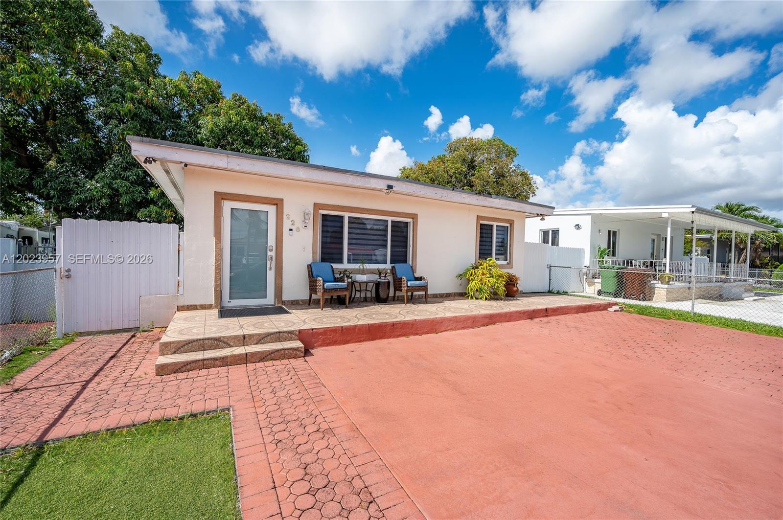 A single-story house with a tiled porch, red paved driveway, and white fence — 228 W 18th St, Hialeah FL 33010, HIALEAH, FL