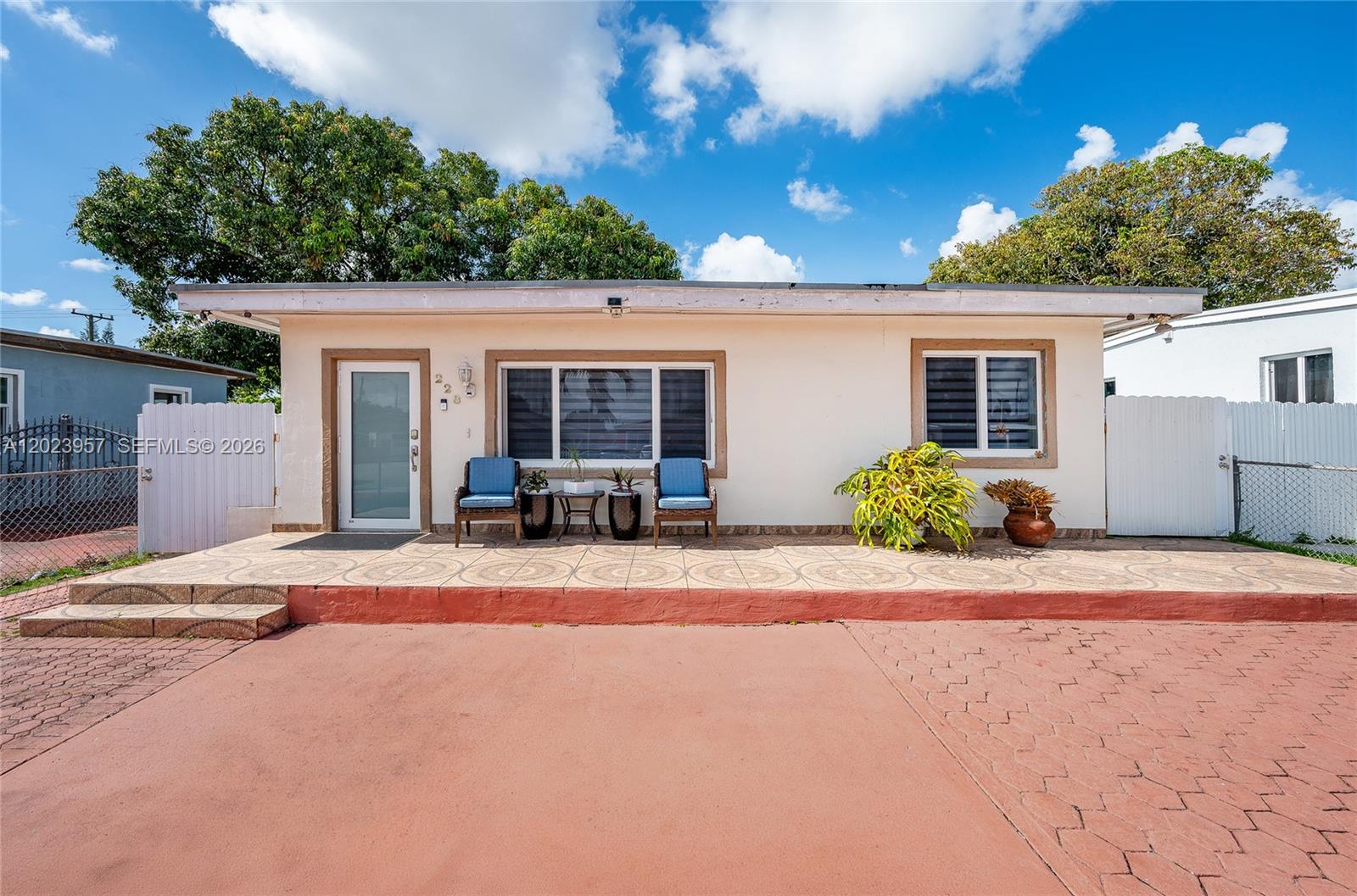 A single-story house with a tiled porch, two blue chairs, and a red concrete driveway — 228 W 18th St, Hialeah FL 33010, HIALEAH, FL