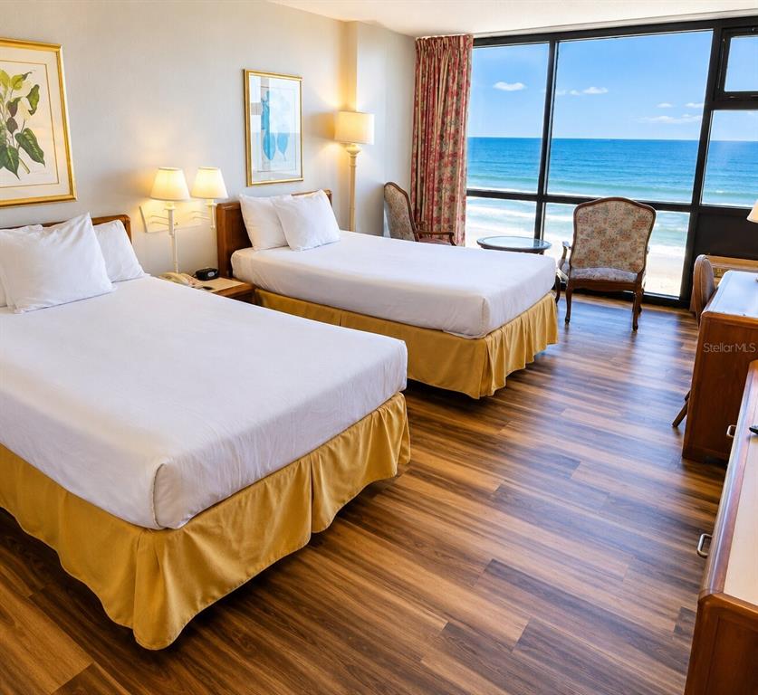 A hotel room with two beds, wood-look flooring, and a large window overlooking the ocean — 1909 S ATLANTIC AVENUE UNIT 714, DAYTONA BEACH, FL