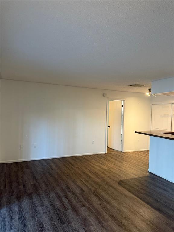An interior view of a living area with wood-look flooring and a kitchen breakfast bar — 3827 BAY CLUB CIR UNIT 103, KISSIMMEE, FL