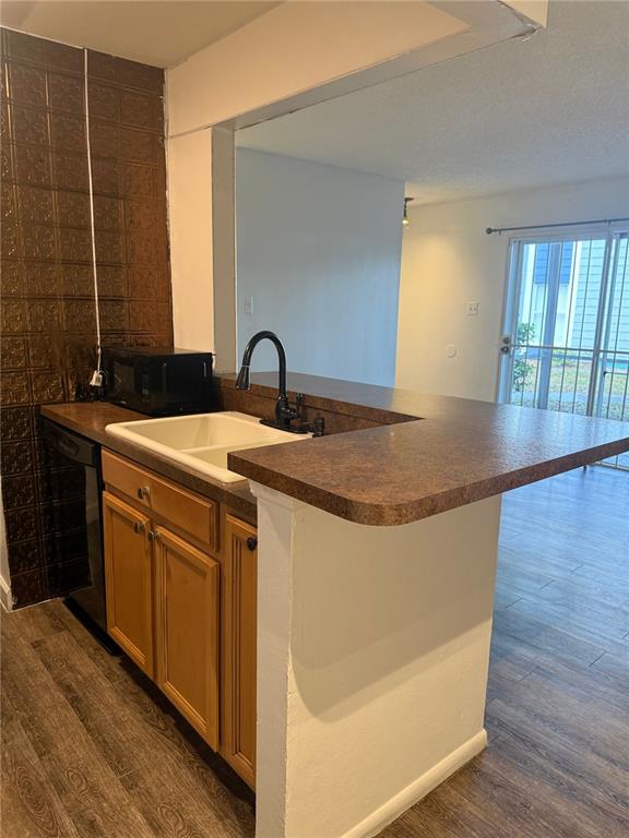 A kitchen features a white sink, brown countertops, wood cabinets, and a textured metal backsplash — 3827 BAY CLUB CIR UNIT 103, KISSIMMEE, FL