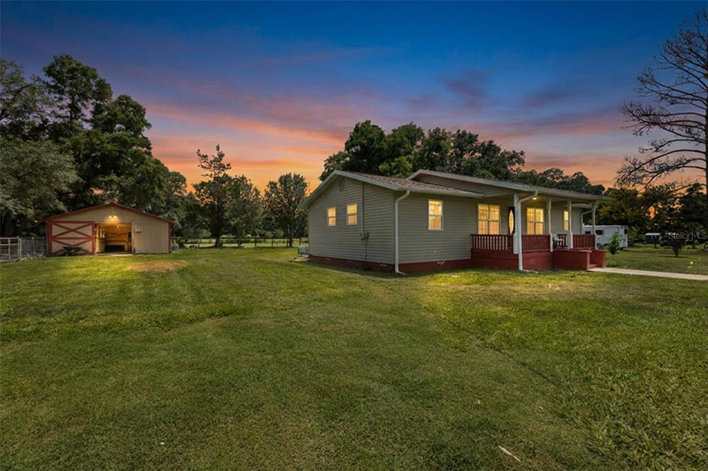 A single-story house with light siding and a detached garage on a grassy lot — 18950 NE 55TH STREET, WILLISTON, FL