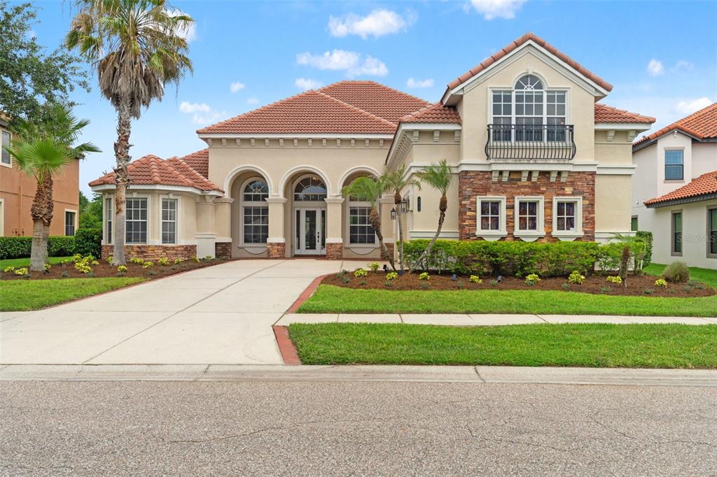 A two-story stucco house with a tile roof, stone accents, and a concrete driveway — 8412 DUNHAM STATION DRIVE, TAMPA, FL