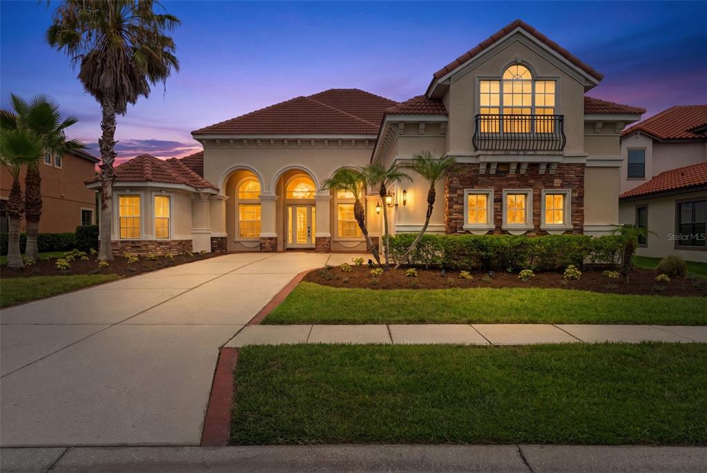 A two-story stucco house with a tile roof, stone accents, and a concrete driveway — 8412 DUNHAM STATION DRIVE, TAMPA, FL