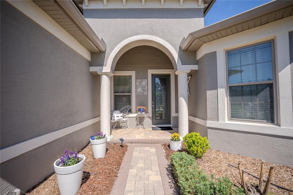 The exterior view shows a paved walkway leading to a covered entryway with two columns — 9186 SW 70TH LOOP, OCALA, FL