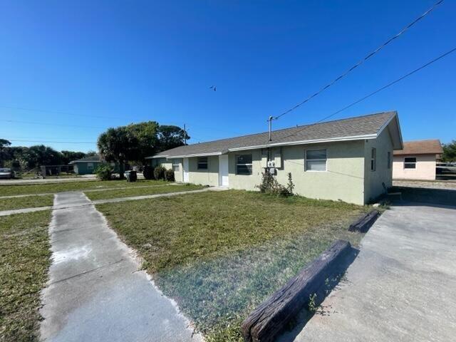 A single-story, light-colored residential building with a shingled roof stands beside a concrete driveway — 1205 Ave K # B, Fort Pierce FL 34950, FORT PIERCE, FL