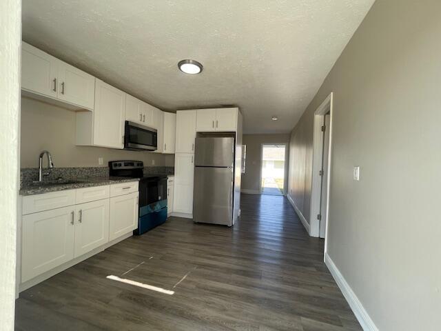 A kitchen features white cabinets, stainless steel appliances, and wood-look flooring — 1205 Ave K # B, Fort Pierce FL 34950, FORT PIERCE, FL
