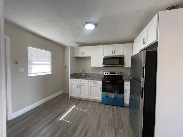 A kitchen features white cabinets, stainless steel appliances, granite countertops, and light wood-look flooring — 1205 Ave K # B, Fort Pierce FL 34950, FORT PIERCE, FL