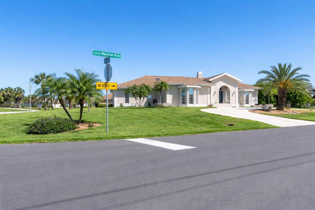 A single-story house with a beige exterior sits on a grassy corner lot — 2 LONG MEADOW ROAD, ROTONDA WEST, FL