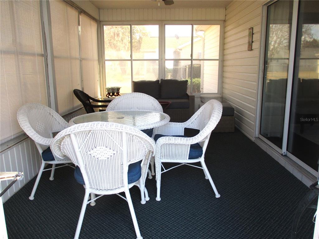 A screened-in patio features a white wicker dining set and a dark gray sofa — 11653 SW 138TH LANE, DUNNELLON, FL