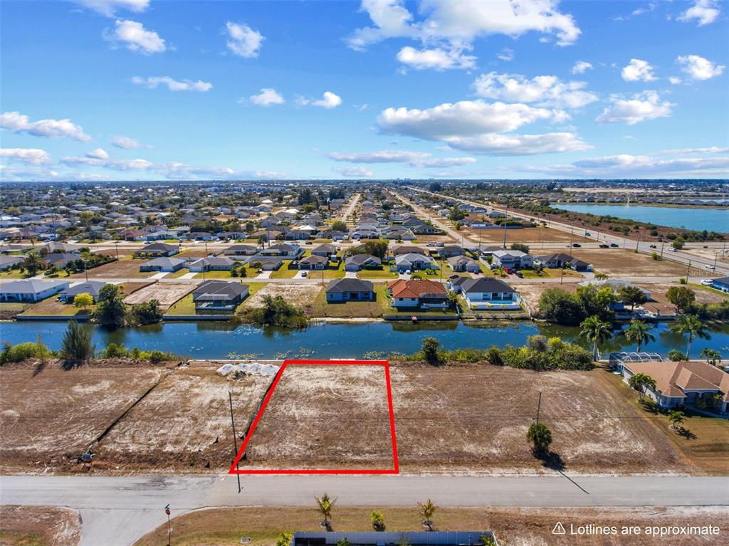 An aerial view shows a vacant rectangular waterfront lot outlined in red — 704 NW 9TH STREET, CAPE CORAL, FL