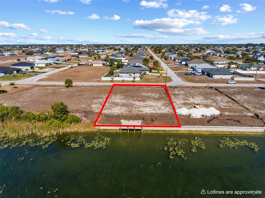 An aerial view shows a vacant waterfront lot outlined in red with a small dock — 704 NW 9TH STREET, CAPE CORAL, FL