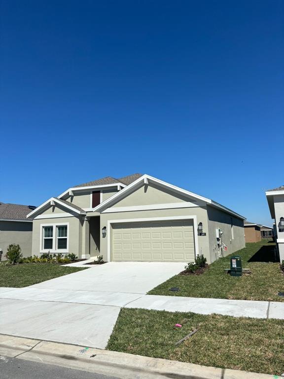 A single-story suburban house with a beige stucco exterior and a two-car garage — 541 HATTERAS ROAD, DAVENPORT, FL
