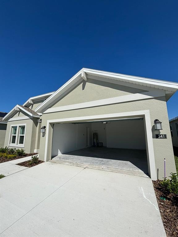 A beige house exterior features a two-car garage, white trim, and a concrete driveway — 541 HATTERAS ROAD, DAVENPORT, FL