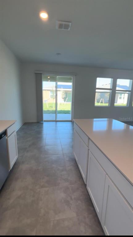 A kitchen island with white cabinets faces a dining area with a sliding glass door — 541 HATTERAS ROAD, DAVENPORT, FL