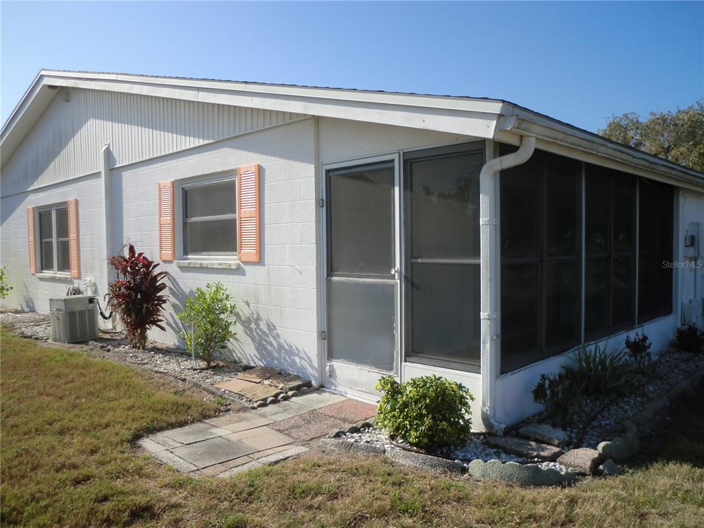 A white house exterior features a screened-in porch, orange shutters, and a small AC unit — 1902 ANDOVER STREET UNIT 203, SUN CITY CENTER, FL