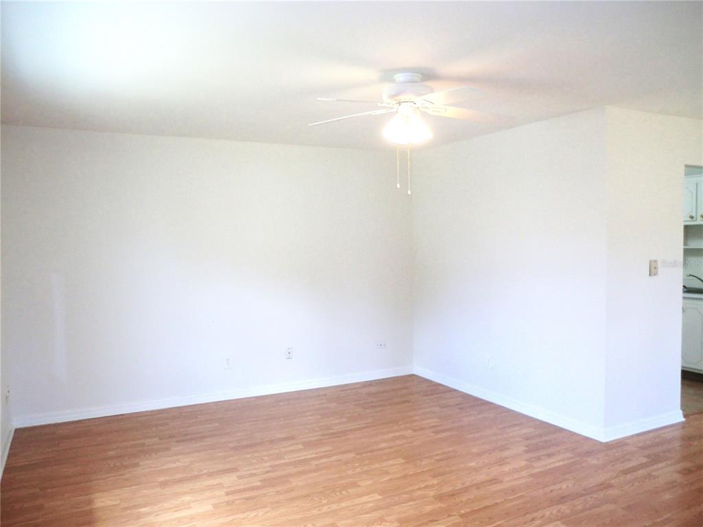 An empty room with white walls, a ceiling fan, and wood-look flooring — 1902 ANDOVER STREET UNIT 203, SUN CITY CENTER, FL