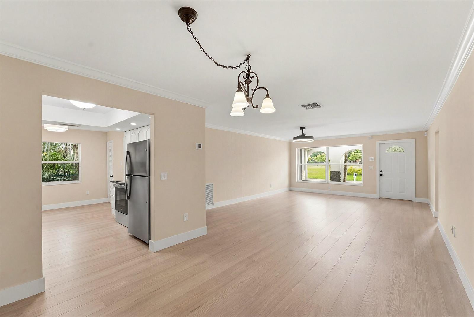 An open-concept living and dining area features light wood flooring, beige walls, and a kitchen — 22267 SW 57th Avenue, Boca Raton FL 33428, BOCA RATON, FL