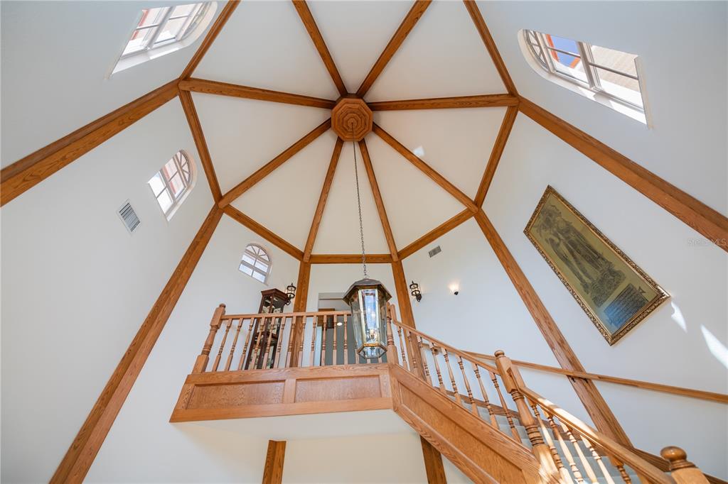 A high-ceilinged foyer features a wooden staircase, a hanging lantern, and exposed wood ceiling beams — 5019 BAL HARBOR BOULEVARD, PUNTA GORDA, FL