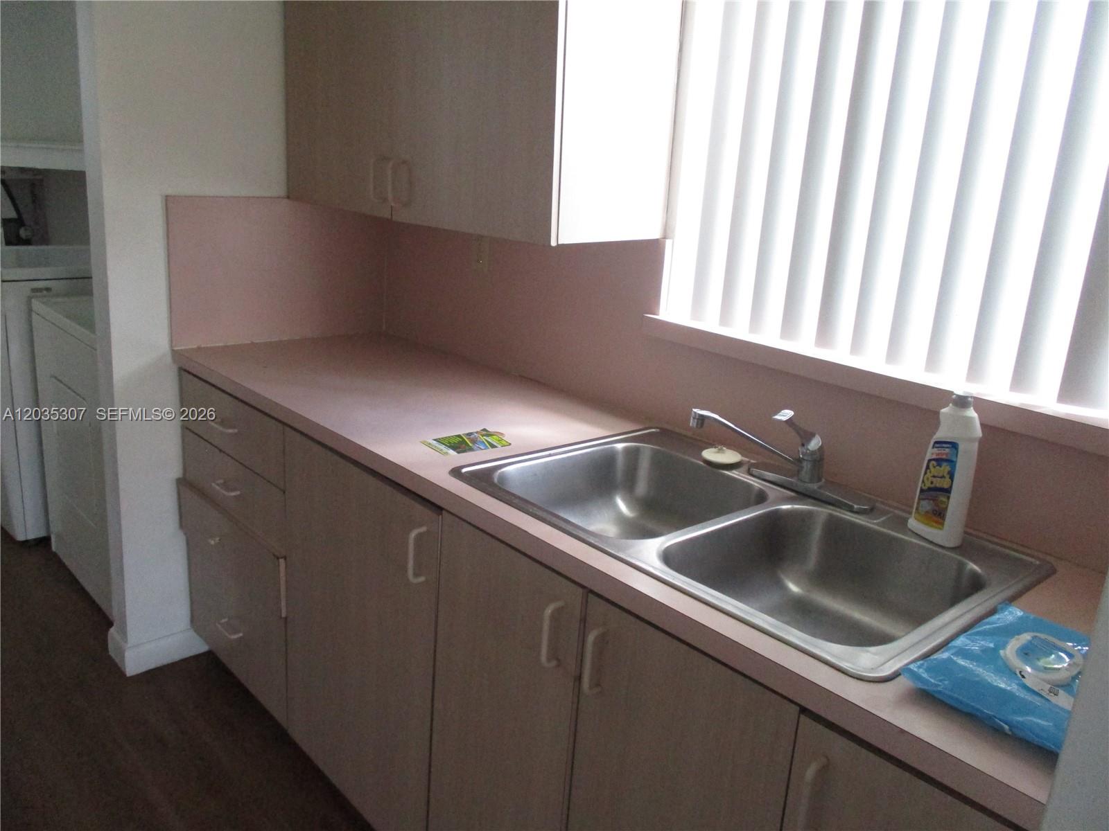 A kitchen features light wood cabinets, a pink countertop, a double sink, and vertical blinds — 10622 SW 174th Ter # 10622, Miami FL 33157, MIAMI, FL