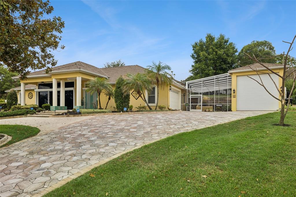 A yellow house with a stone driveway, a screened-in patio, and a detached garage — 12128 LAKESHORE DRIVE, CLERMONT, FL