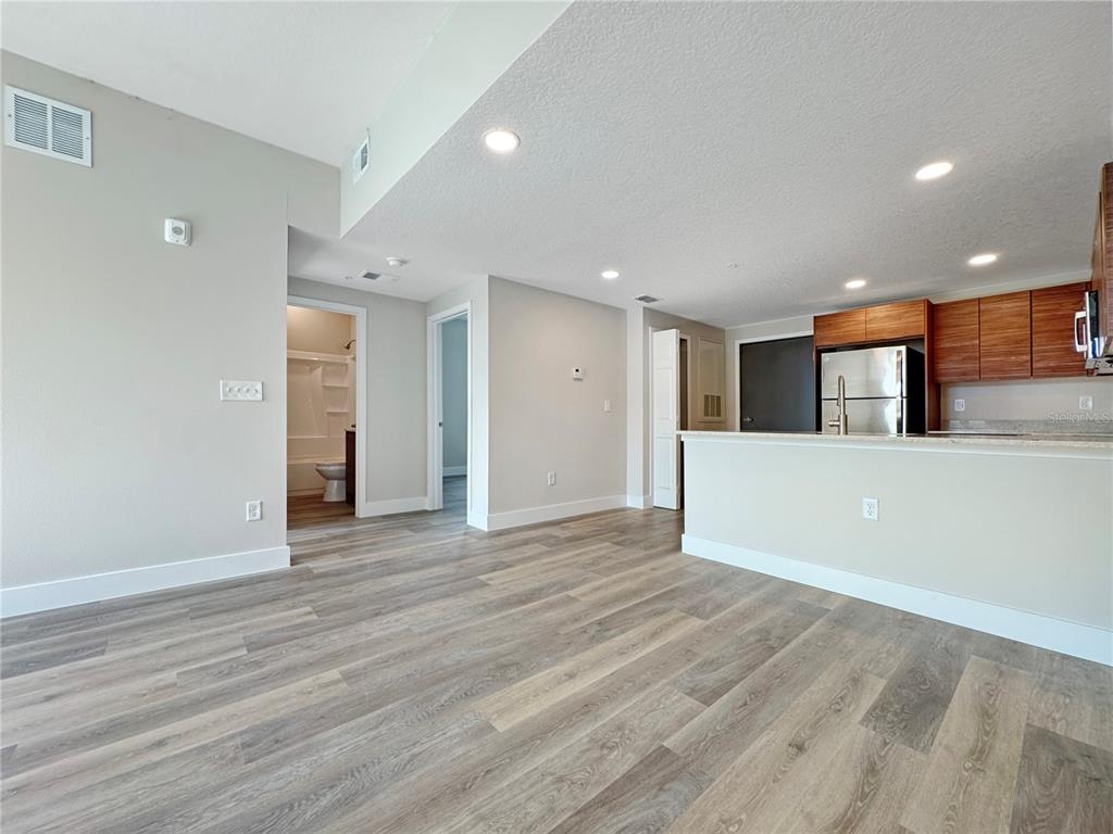 An open-concept living area features wood-look flooring, recessed lighting, and a kitchen with wood cabinets — 4424 S TEXAS AVENUE UNIT 1-320, ORLANDO, FL