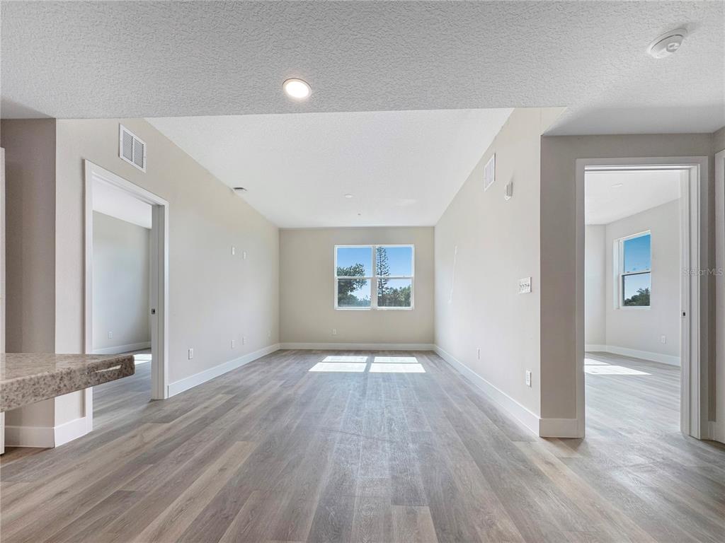 An empty room with light-colored walls, gray wood-look flooring, and two doorways leading to other rooms — 4424 S TEXAS AVENUE UNIT 1-320, ORLANDO, FL
