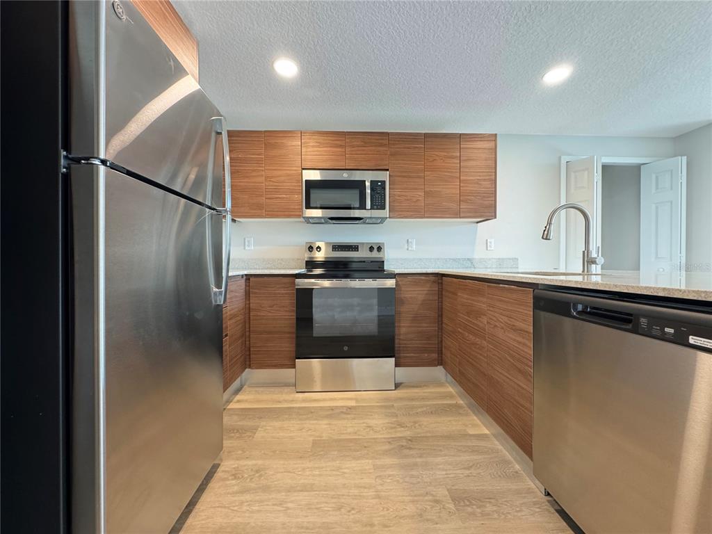 A kitchen features stainless steel appliances, wood-grain cabinets, and light-colored countertops — 4424 S TEXAS AVENUE UNIT 1-320, ORLANDO, FL