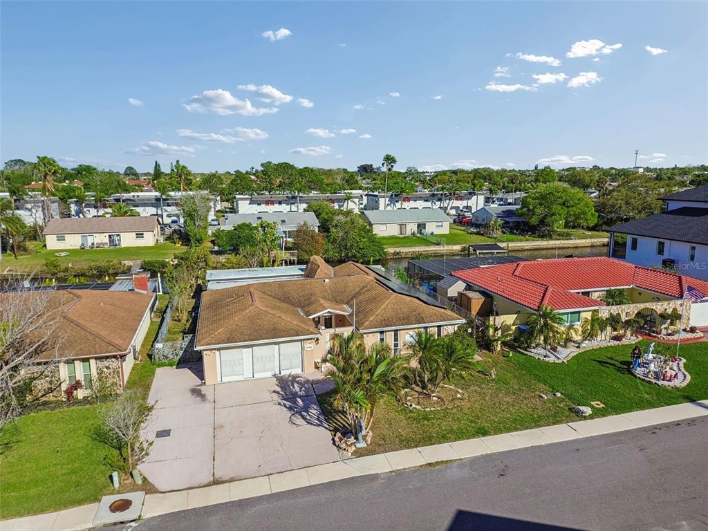 An aerial view shows a single-story house with a brown roof and a concrete driveway — 9900 ISLAND HARBOR DRIVE, PORT RICHEY, FL