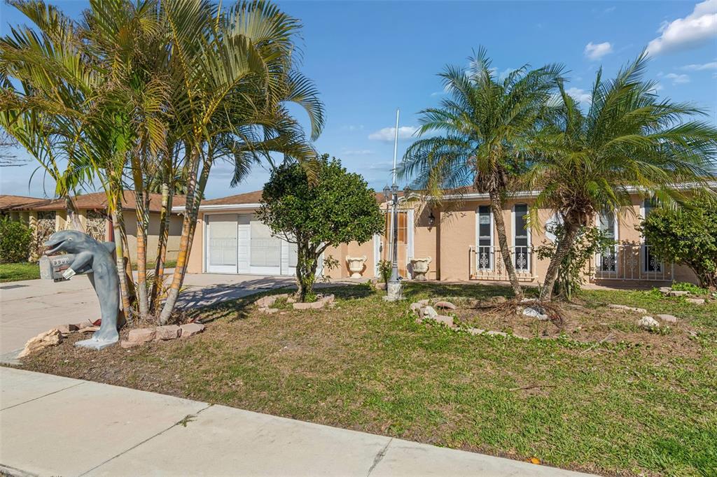 A single-story house with a dolphin-shaped mailbox, palm trees, and a concrete driveway — 9900 ISLAND HARBOR DRIVE, PORT RICHEY, FL