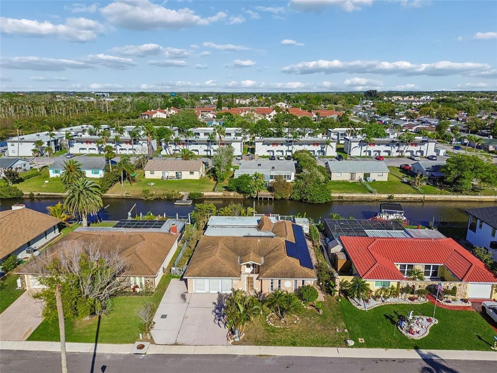 An aerial view shows a row of suburban houses with solar panels along a canal — 9900 ISLAND HARBOR DRIVE, PORT RICHEY, FL
