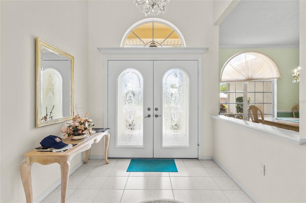 A bright entryway features white tile floors, a double front door, and a console table — 832 CARNOUSTIE DRIVE, VENICE, FL